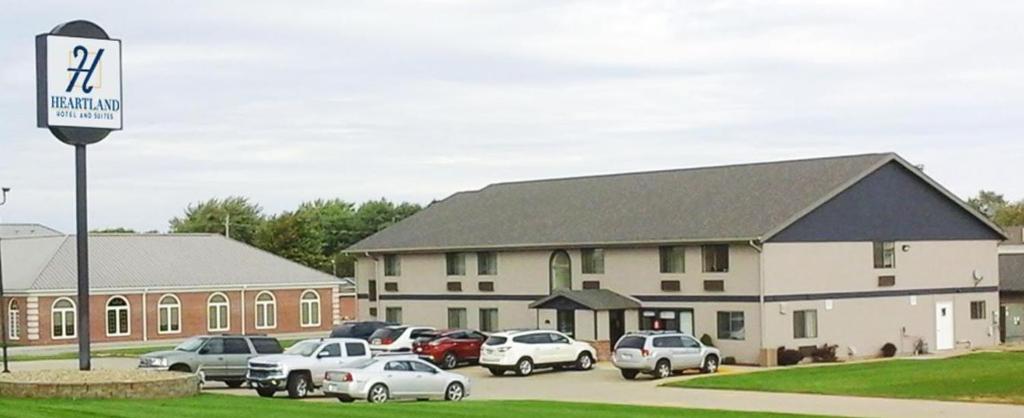 un estacionamiento con autos estacionados frente a un edificio en Heartland Hotel & Suites en Rock Valley