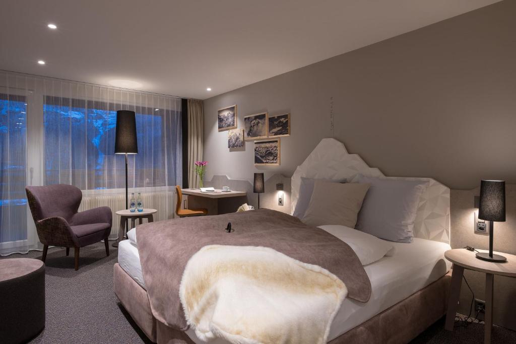 - une chambre avec un grand lit et une chaise dans l'établissement Sunstar Hotel & SPA Grindelwald, à Grindelwald