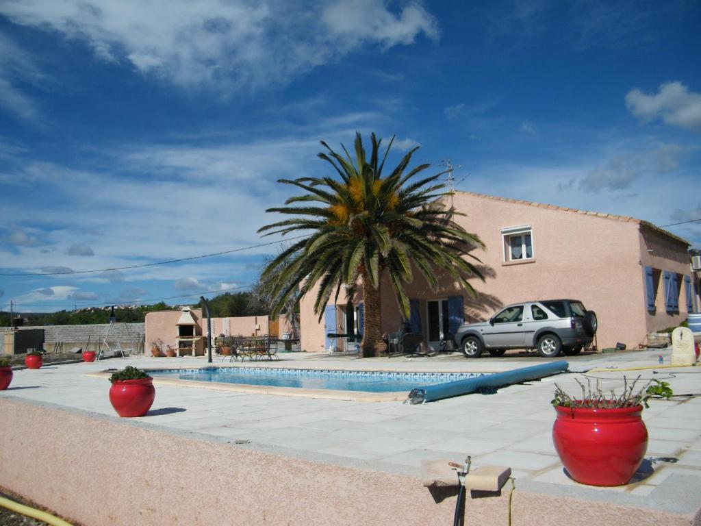 een huis met een palmboom naast een zwembad bij La piscine in Fitou