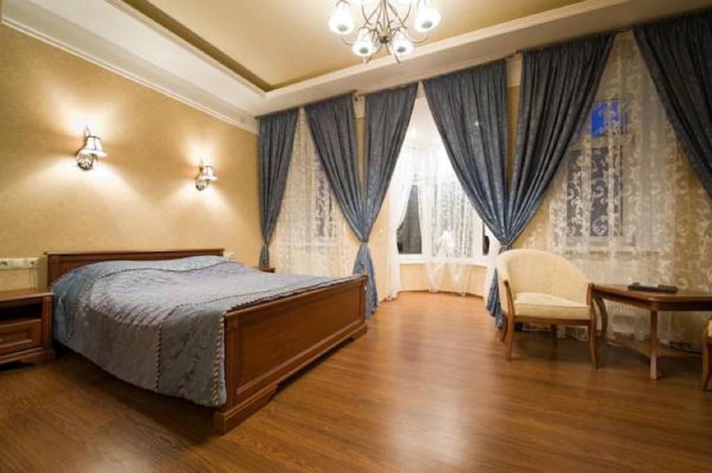 een slaapkamer met een bed, een stoel en een raam bij Hotel on Dvoryanskaya in Kaloega