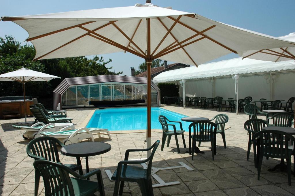 uma piscina com mesas e cadeiras e um guarda-sol em The Originals City, Hôtel Le Boeuf Rouge, Saint-Junien em Saint-Junien