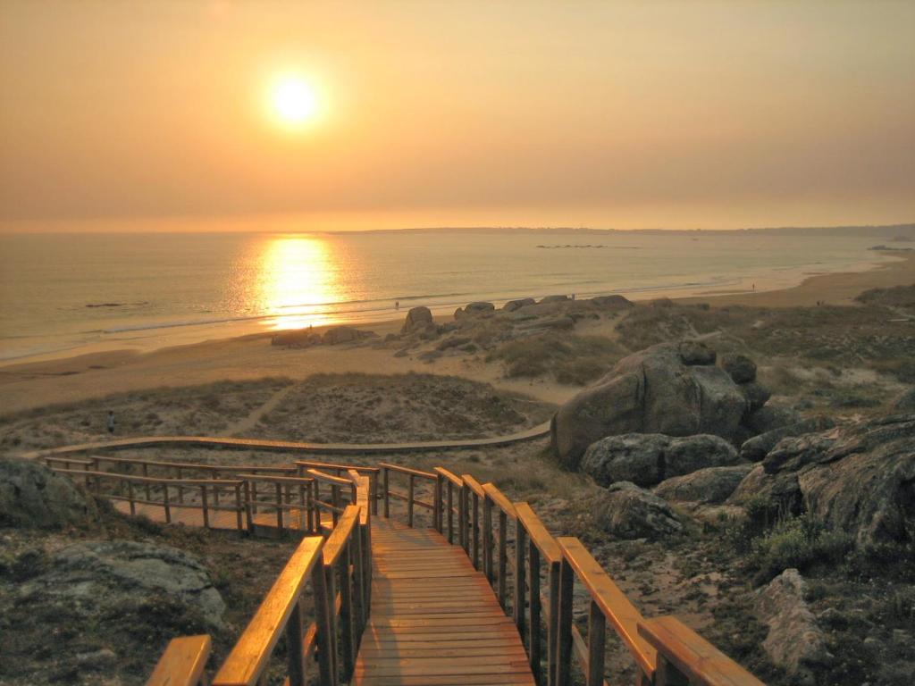 un sentiero in legno per la spiaggia al tramonto di Alquiler Vacacional en Ribeira a Ribeira