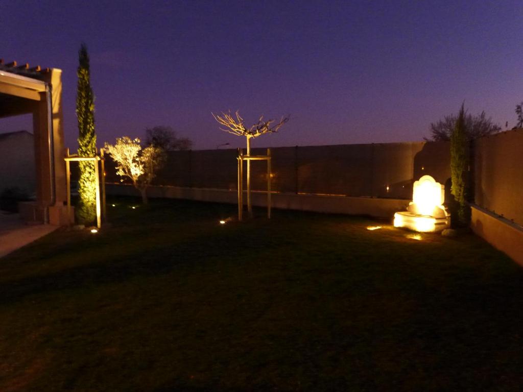 a backyard at night with lights on a fence at Les Trois Oliviers in Forcalquier