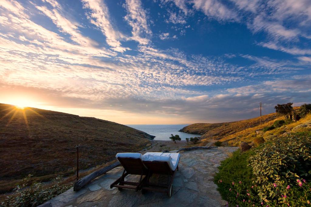 a bench sitting on a stone path next to the ocean at Amelia Beachfront Villa in Korissia