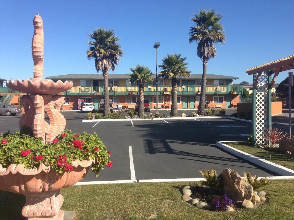 a parking lot with a hotel and palm trees at Sand Castle Inn in Seaside