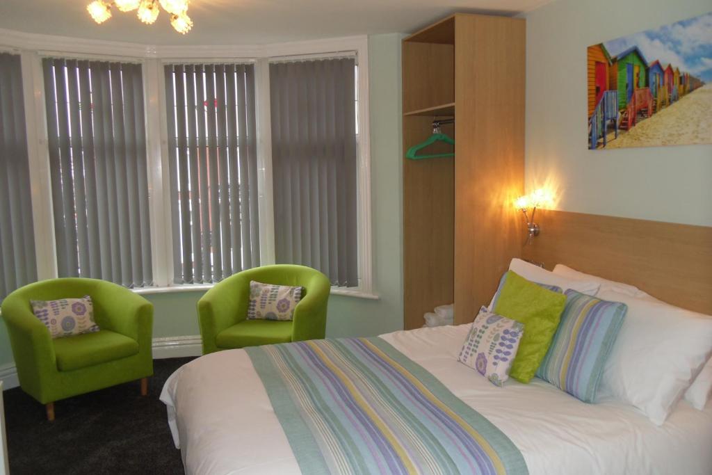 um quarto com uma cama e 2 cadeiras verdes em The Beaucliffe em Blackpool