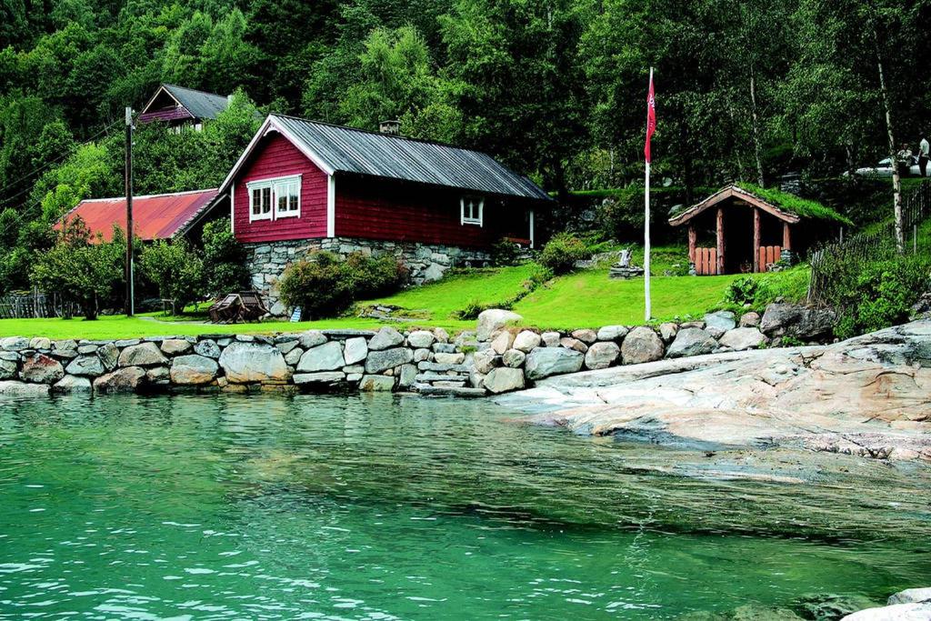 una casa roja junto a un río con una pared de piedra en Bodvarstova en Stryn