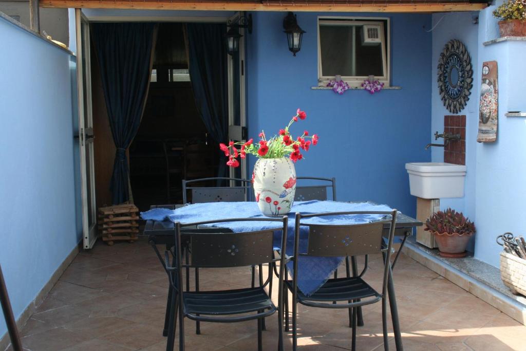 een tafel met stoelen en een vaas met bloemen erop bij Casa vacanze Aloha in Giardini Naxos