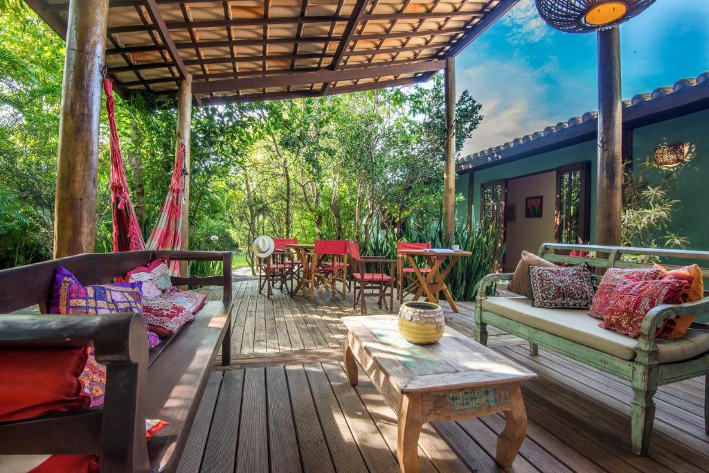 a porch with couches and a table on a deck at Casa Morada dos Pássaros in Imbassai