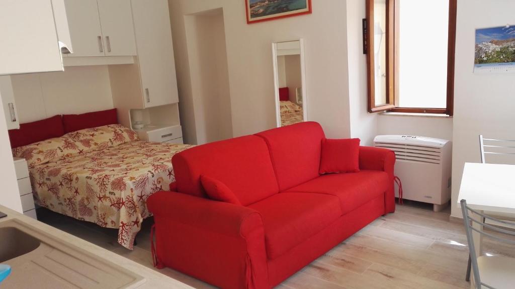 a living room with a red couch and a bed at Appartamento Madda in La Maddalena