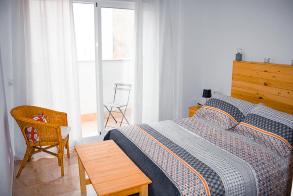 - une chambre avec un lit, une chaise et une fenêtre dans l'établissement Apartamento Juan de Herrera, à Malaga