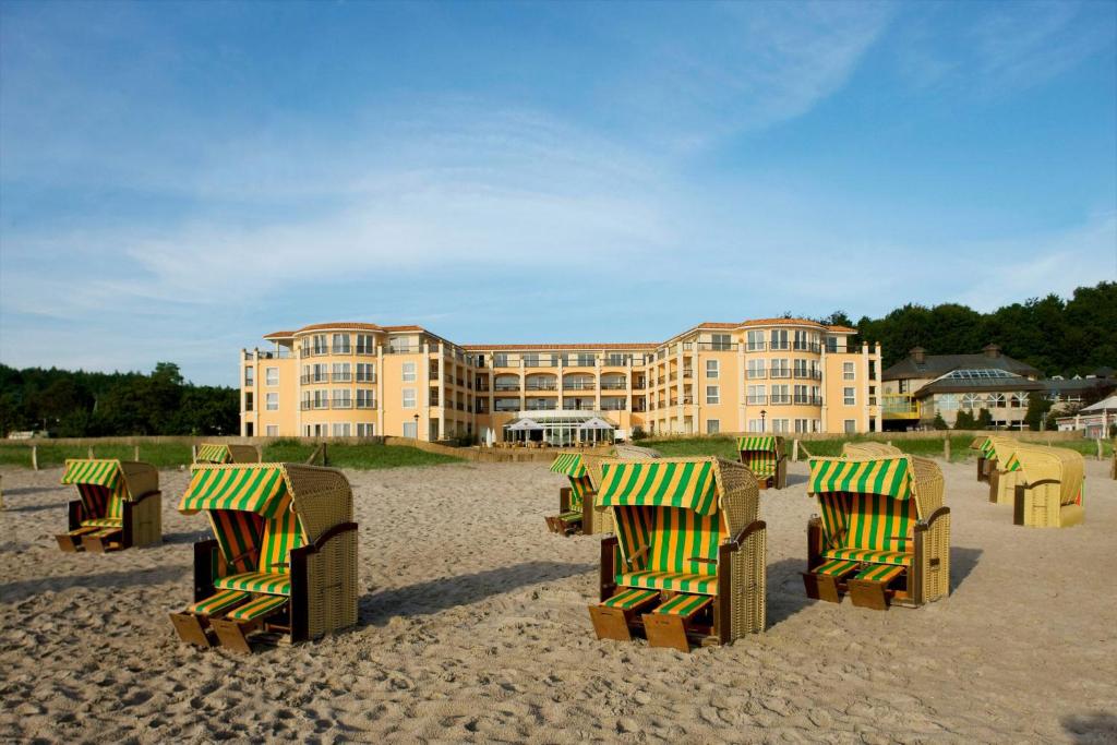 a group of chairs on the beach in front of a building at Hotel Gran BelVeder & Ostsee Therme Resort & Spa in Scharbeutz