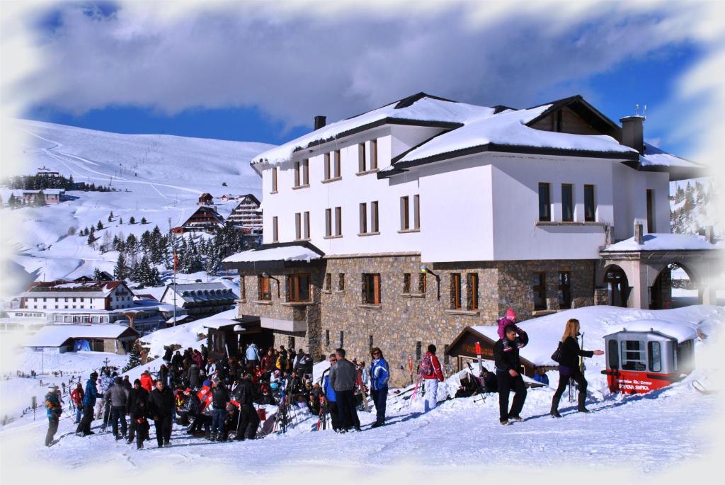 un grupo de personas de pie en la nieve frente a un edificio en Konak - Popova Sapka en Popova Shapka