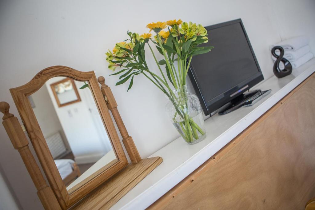 a vase of flowers sitting on a counter next to a mirror at St Breca in Newquay