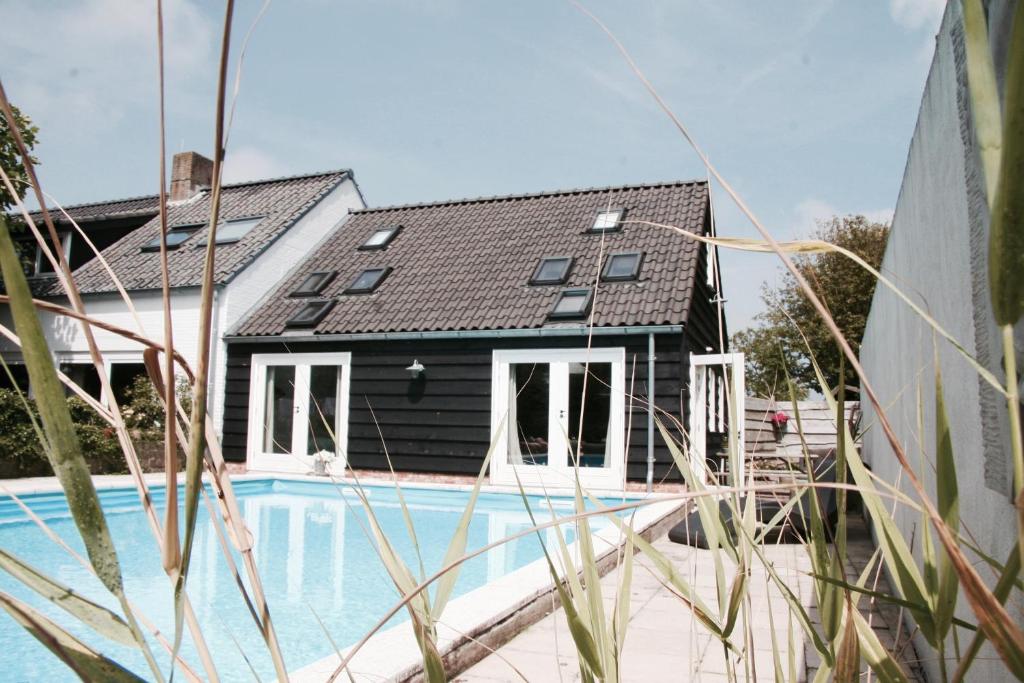 a black house with a black roof and a swimming pool at Bed & Breakfast Zeeland in Renesse