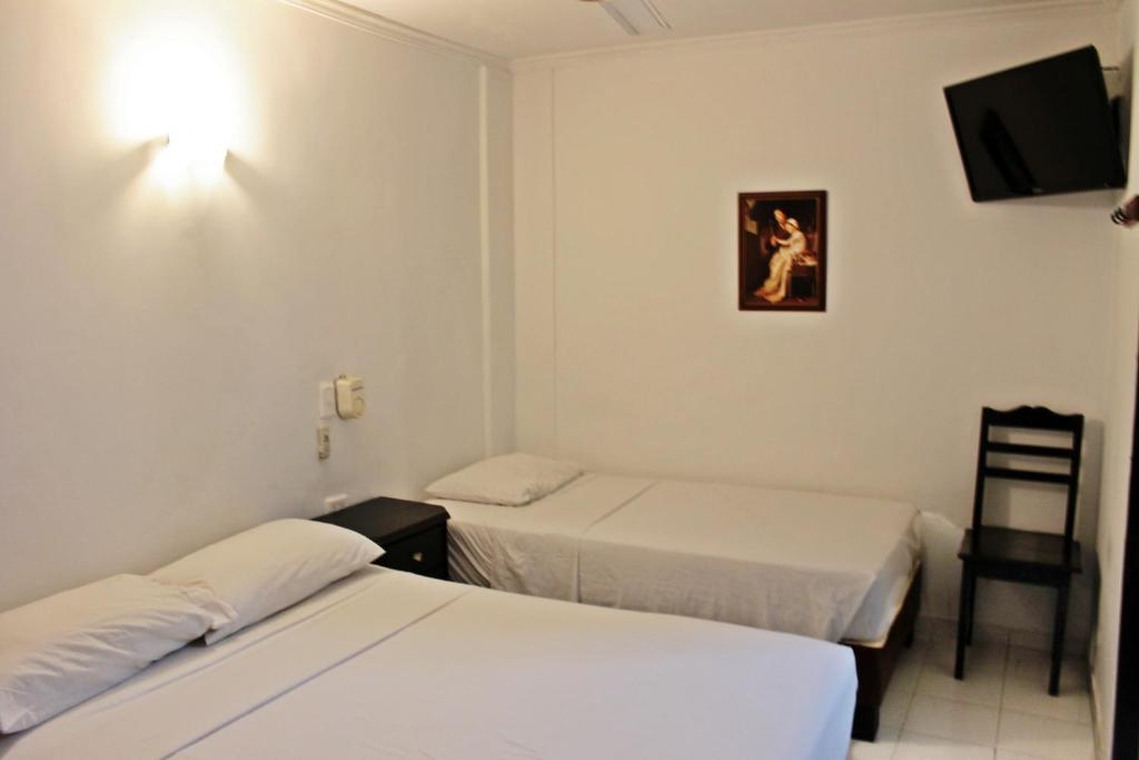カルタヘナ・デ・インディアスにあるHotel Villa Colonial By Akel Hotelsのベッド2台とテレビが備わるホテルルームです。