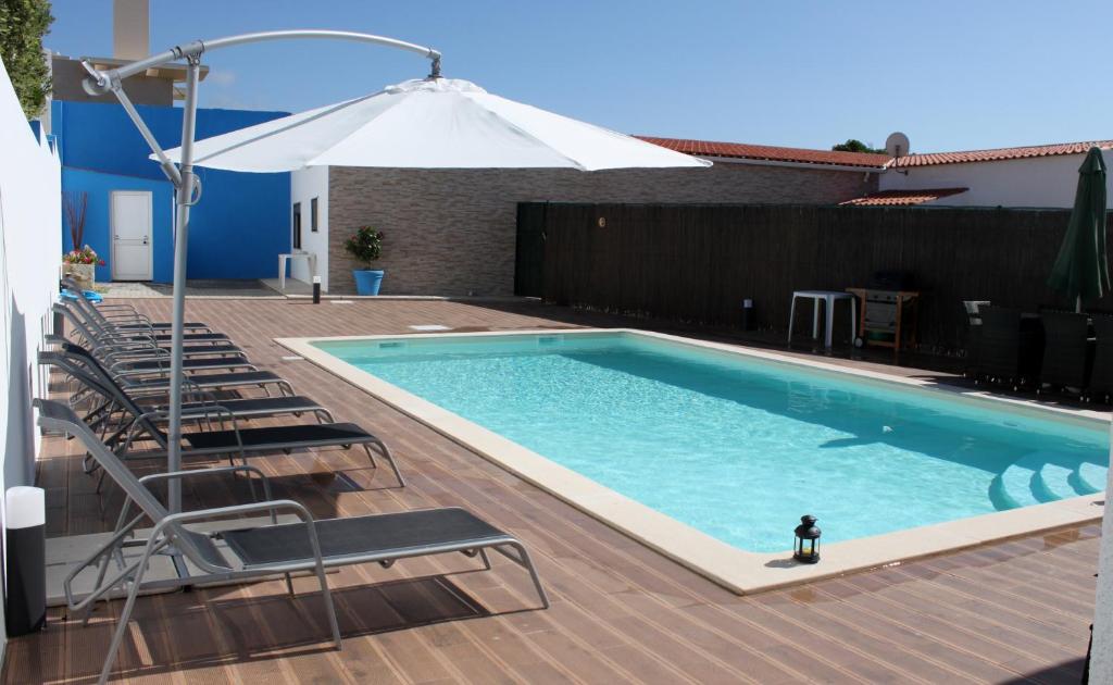 a swimming pool with chairs and an umbrella at Vila Private Pool Beach Golf Praia Del Rey in Amoreira