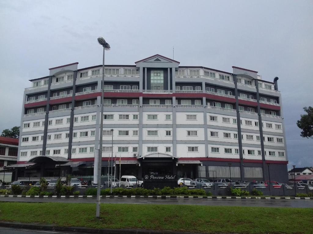 a large white building with cars parked in front of it at Penview Hotel in Kuching