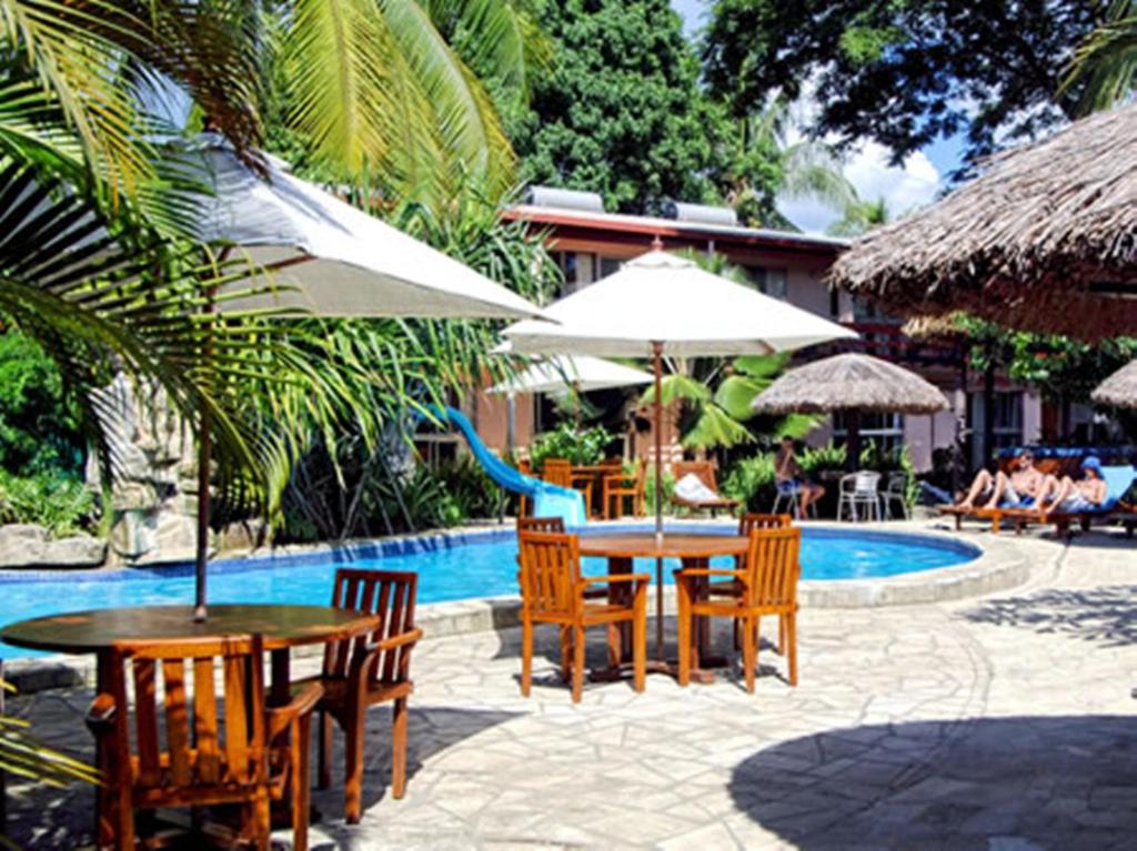 a patio with a table and chairs next to a pool at Capricorn International Hotel in Nadi