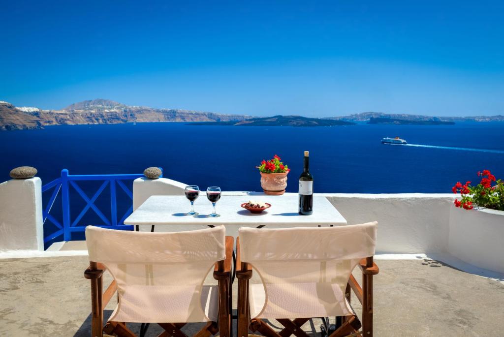 a table with two glasses of wine and a view of the ocean at Chelidonia Traditional Villas in Oia