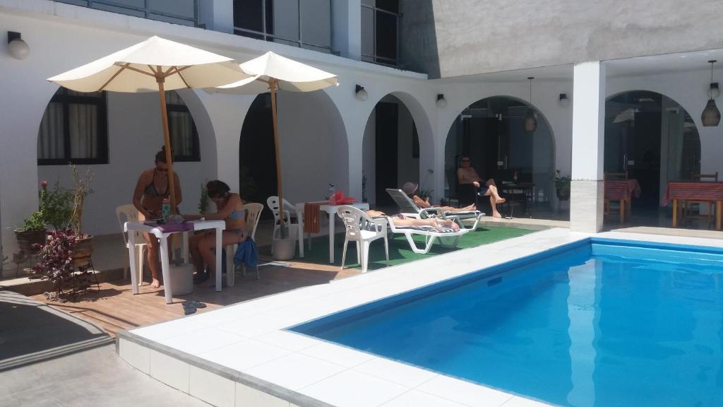 a group of people sitting next to a swimming pool at La Maison de Lydia in Nazca