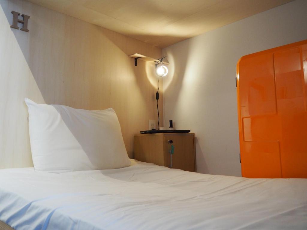 een slaapkamer met een wit bed en een lamp bij Tomarigi Hostel Cafe Bar in Kochi