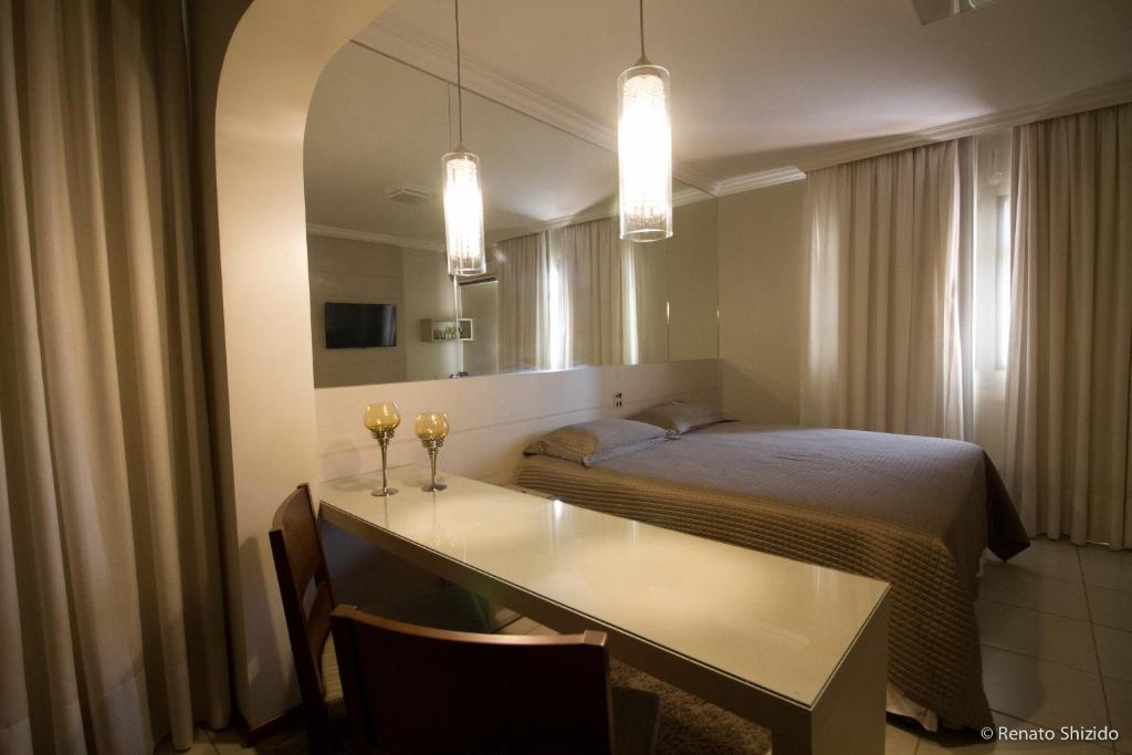 a bedroom with a bed and a table and a mirror at Aruá Hotel in Presidente Prudente