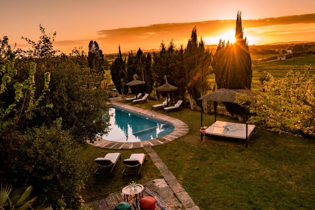 a pool with chairs and umbrellas in a garden at Fincahotel Son Valls in Felanitx