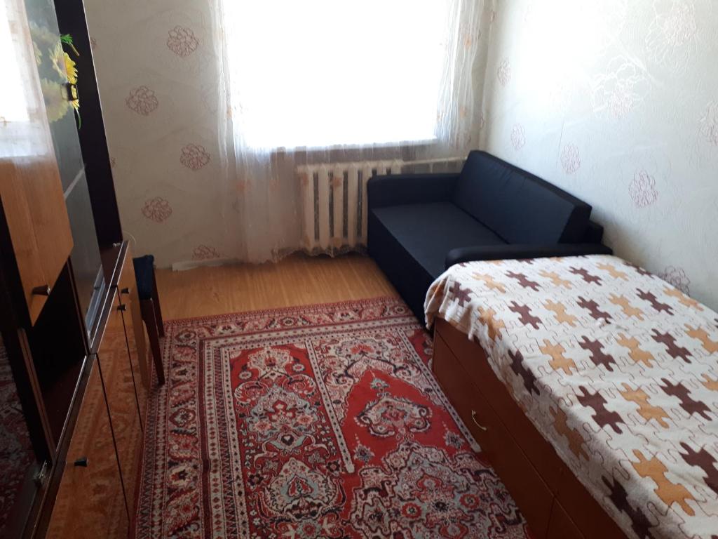 1 dormitorio con cama, alfombra y ventana en Apartment on Gagarina 2, en Zlatoust