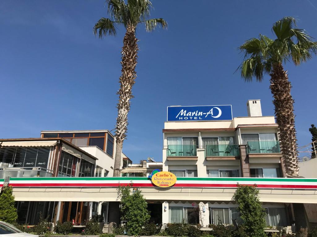 a large building with palm trees in front of it at Marin-A Hotel & Spa Turgutreis in Turgutreis