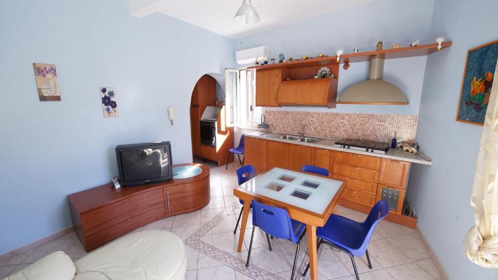カンポフェリーチェ・ディ・ロッチェッラにあるCasa Eleonoraのキッチン(テーブル、青い椅子、テレビ付)