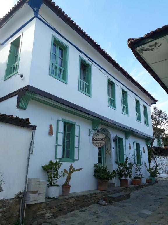 um edifício branco com janelas verdes e vasos de plantas em Kirkinca Hotel em Selçuk