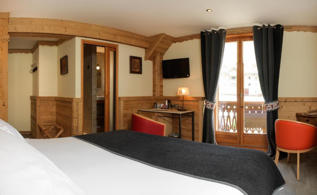 a bedroom with a bed and a desk and a television at Auberge du Manoir in Chamonix
