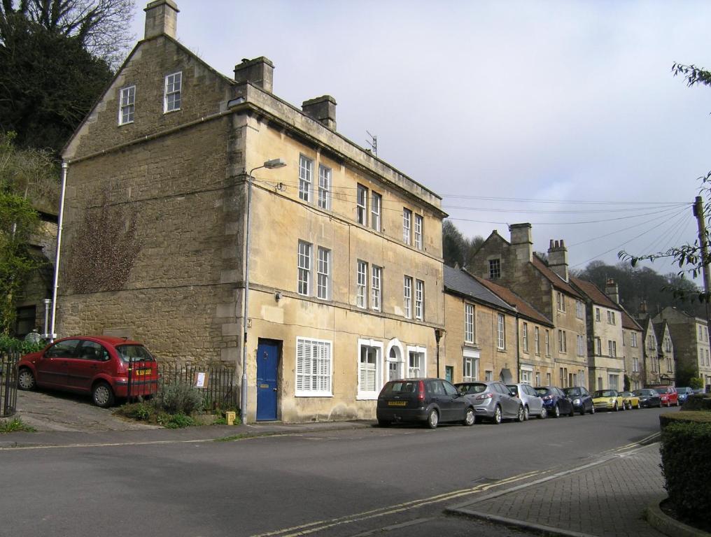 een oud bakstenen gebouw in een straat met geparkeerde auto's bij 38 Newtown in Bradford on Avon
