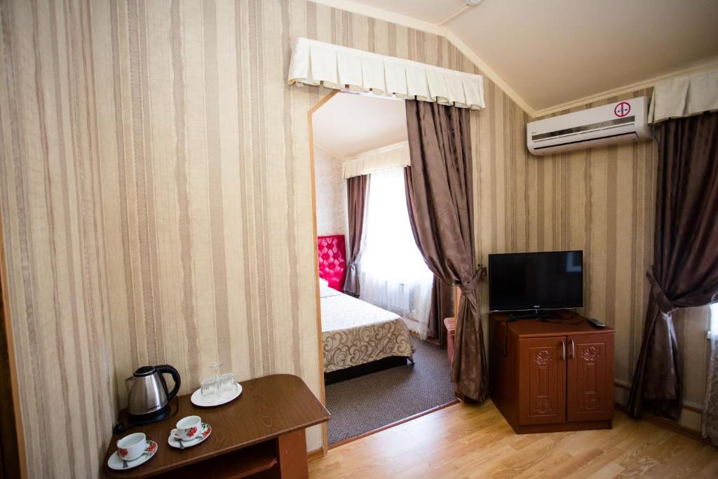 a hotel room with a bed and a television at Guest House Uyut in Tuapse