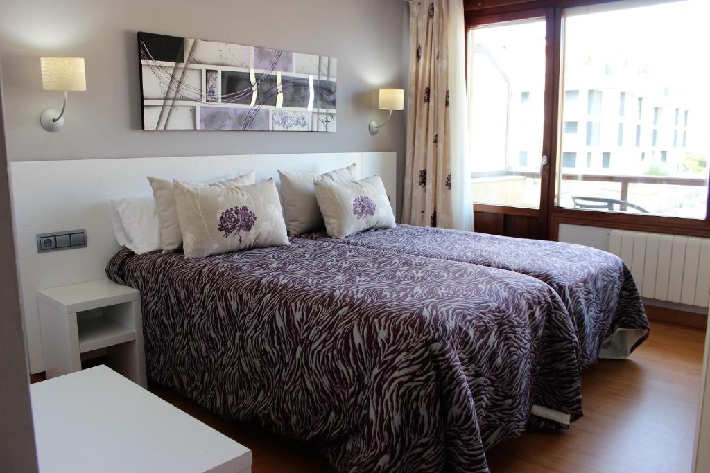 a bedroom with a bed with a purple blanket at Hotel Las Olas in Noja