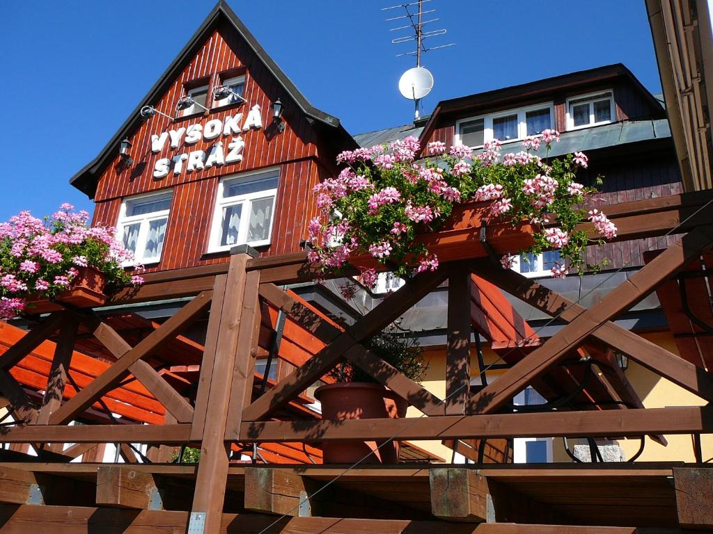 een houten gebouw met bloemen op een houten hek bij penzion Vysoká Stráž in Pec pod Sněžkou