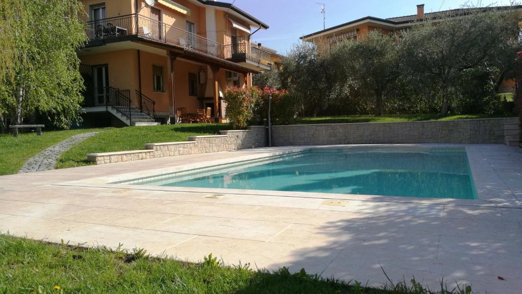 a swimming pool in a yard next to a house at Appartamenti Villacedro in Lazise