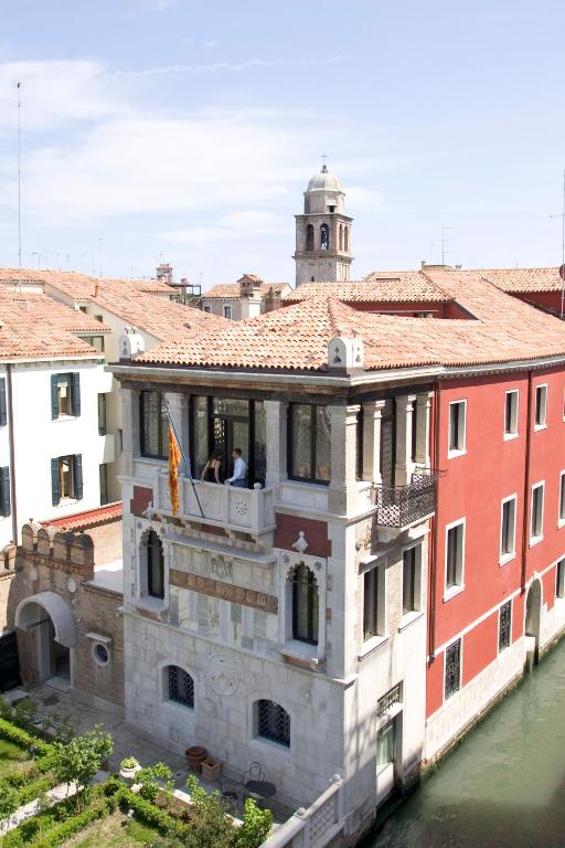 a building with two people on a balcony next to a river at Ca' Nigra Lagoon Resort Adults Only in Venice