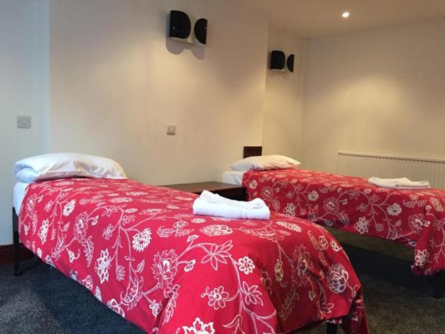 two beds in a room with red sheets and towels at Four Stars Hotel in London