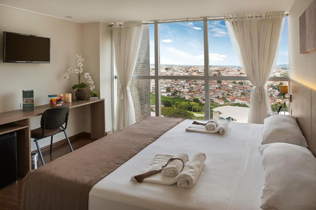 - une chambre avec un grand lit et des serviettes dans l'établissement Tryp by Wyndham Varginha Cafe Royal, à Varginha