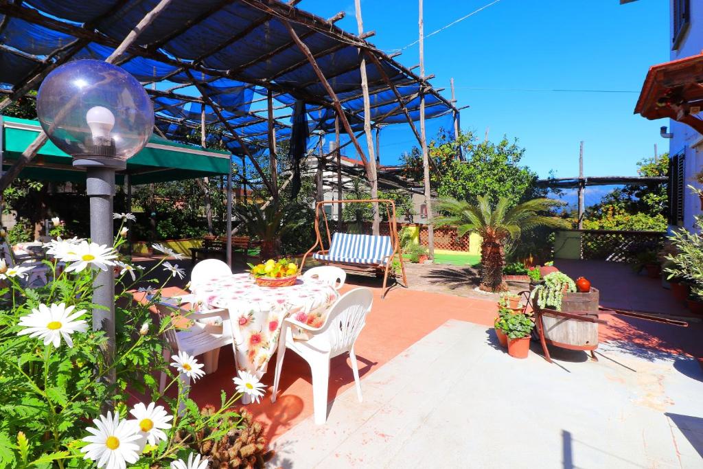 un patio con mesa, sillas y flores en La Maison de Titty & Margherita, en Piano di Sorrento