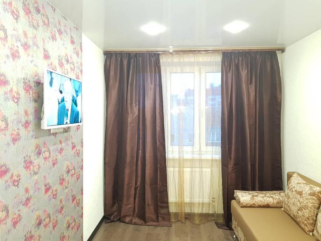キーロフにあるАпартаментыのリビングルーム(茶色のカーテン付きの窓付)