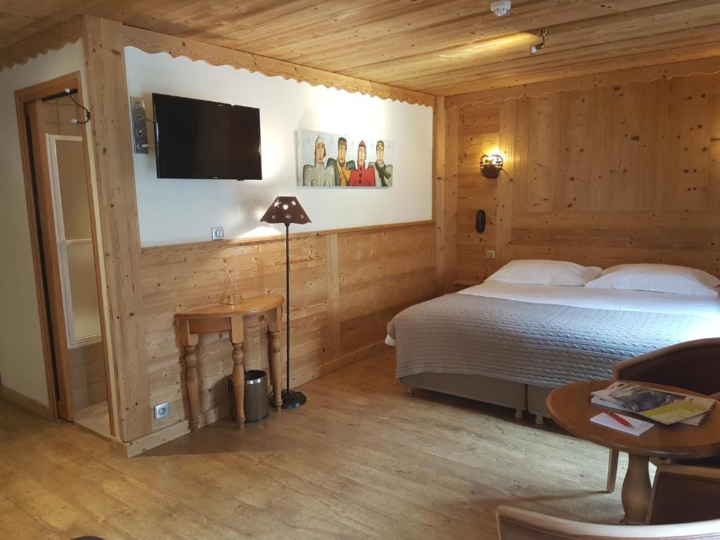 a bedroom with a bed and a tv on a wall at Auberge du Manoir in Chamonix