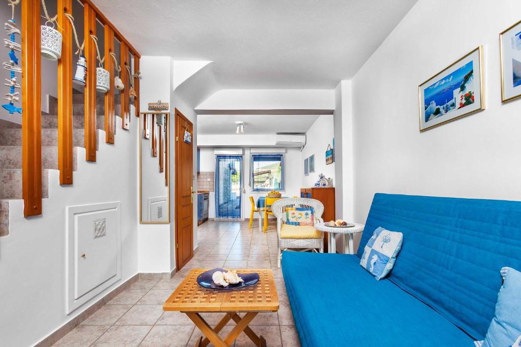 a living room with a blue couch and a table at Gerakini Sunshine Holiday Homes in Yerakiní