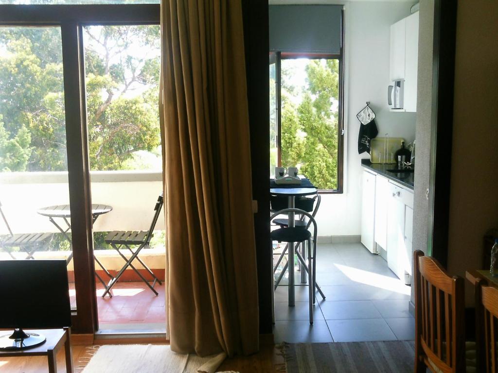 eine Küche mit Blick auf einen Tisch und einen Balkon in der Unterkunft Apartment Troia Garden in Troia