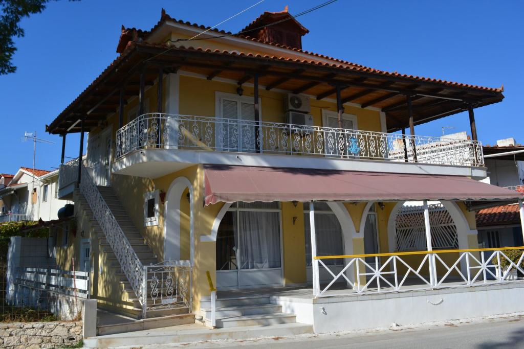 Una casa amarilla con balcón y escaleras. en Villa Anna Alykes en Alykes