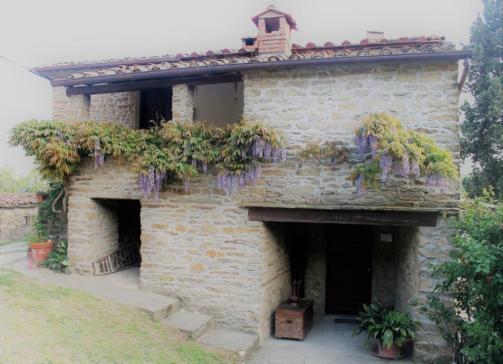 a stone building with purple flowers on it at Casa Manu in Capolona