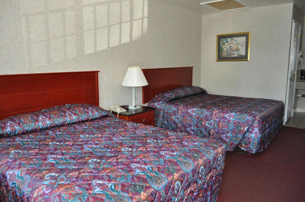 a hotel room with two beds and a lamp at Atrium Inn & Suites in Galloway