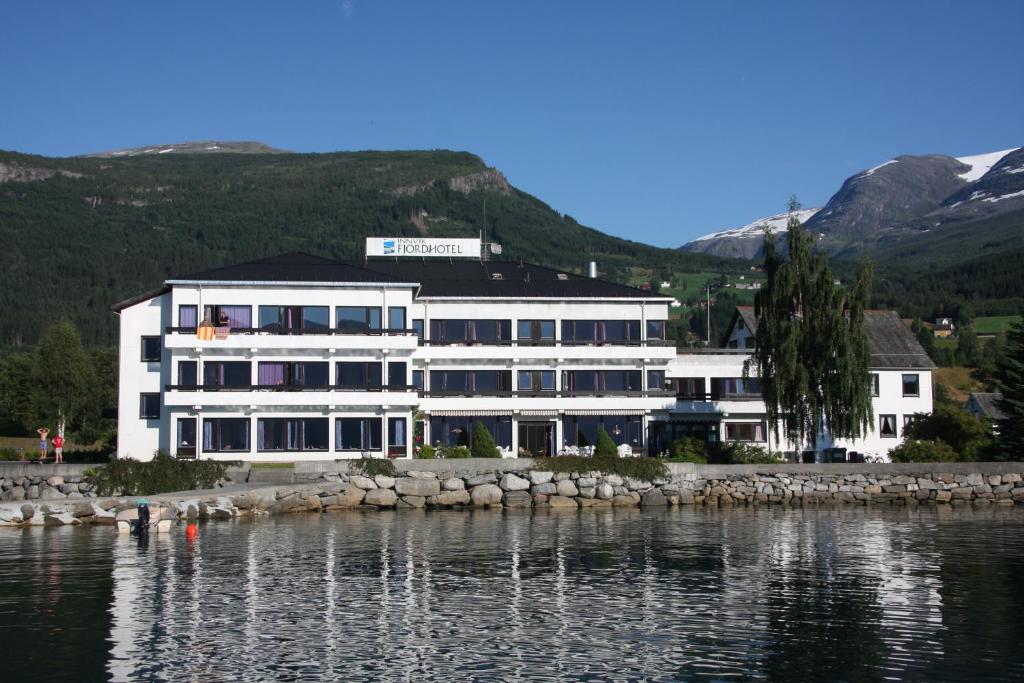 a large white building next to a body of water at Innvik Fjordhotell in Innvik